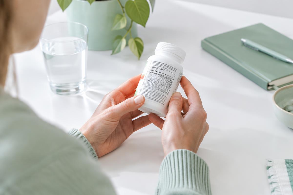 Illustrative scene of a person checking the back label of a generic supplement bottle
